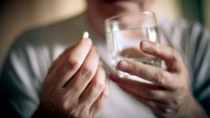 Closeup of man getting ready to take a pill with water