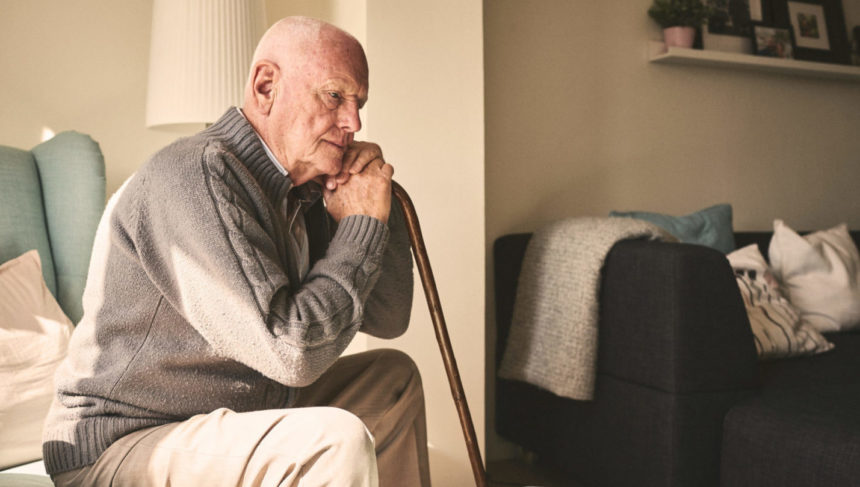 Image of older man with cane, sitting alone