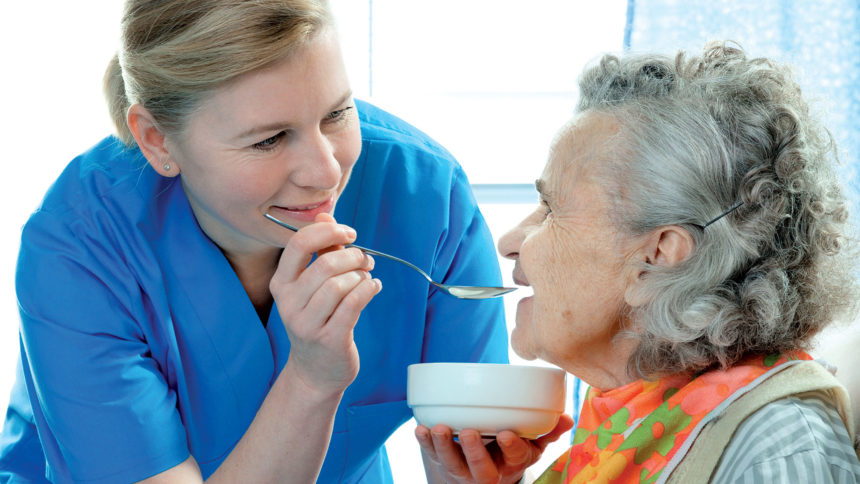 Caregiver feeding senior with dementia