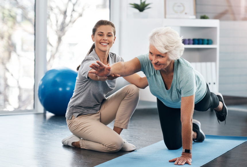 Image of senior woman receiving physical therapy from therapist on exercise mat