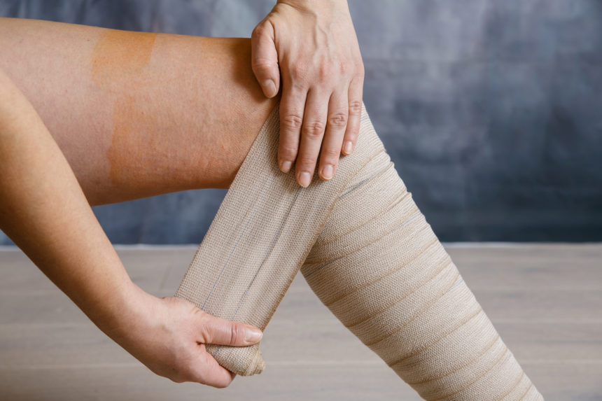 Woman putting compression bandage on leg