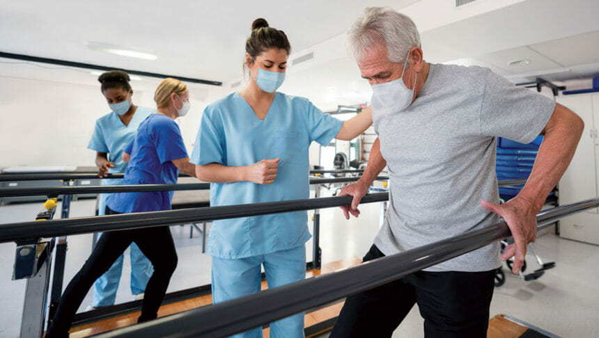 Image of patient getting assistance with walking by clinician in a rehabilitation facility