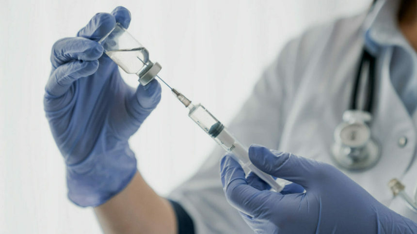 Closeup of clinician's hands getting vaccine dose ready