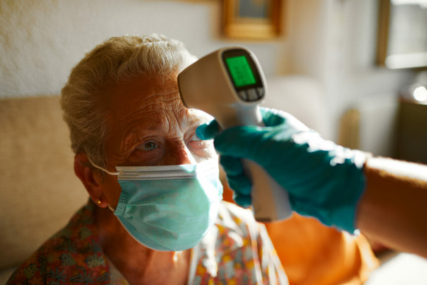 Closeup image of senior woman getting temperature check with an infrared thermometer; Credit: GettyImages-1256717963.jpg