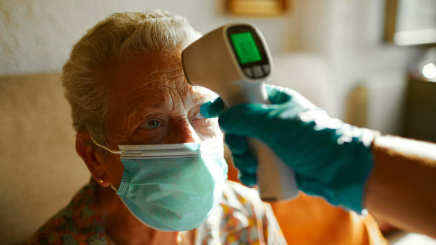Closeup image of senior woman getting temperature check with an infrared thermometer; Credit: GettyImages-1256717963.jpg