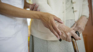 Close up image of a caretaker helping older woman walk