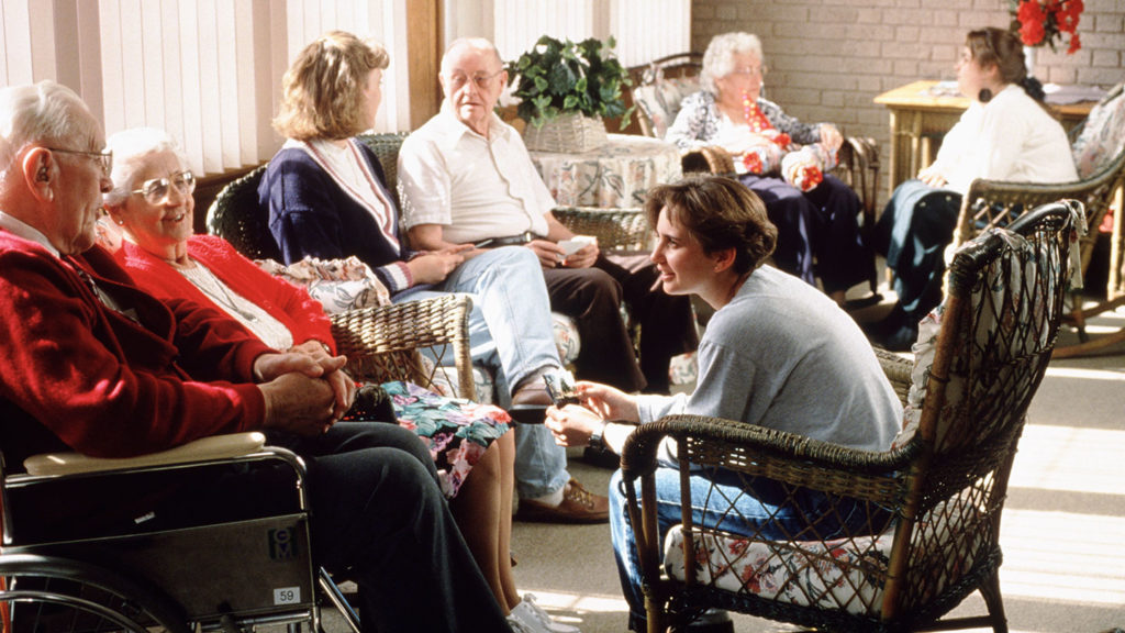 A group of nursing home residents laugh and talk with each other