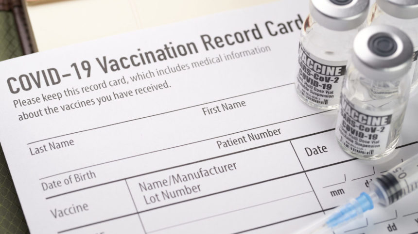 Image of Covid-19 vaccination record card with vials and syringe.