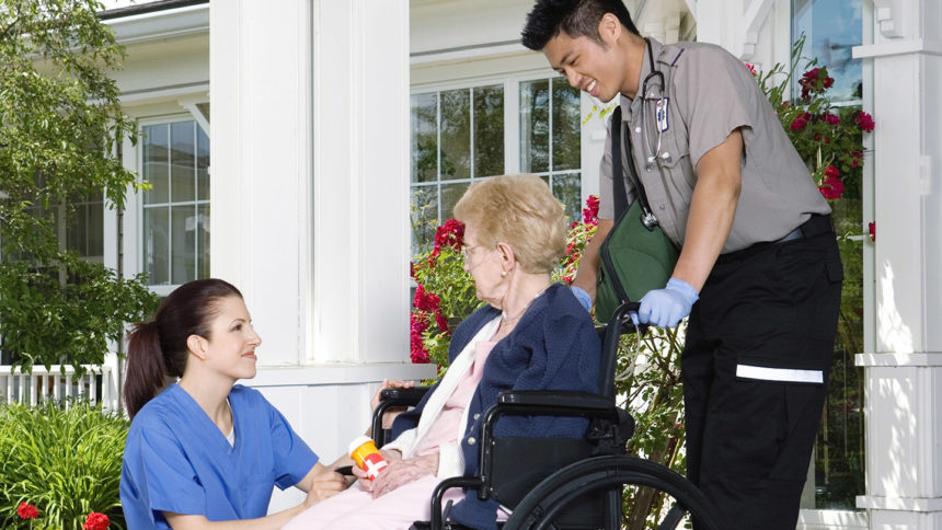 Paramedic and nurse talking to senior woman in wheelchair