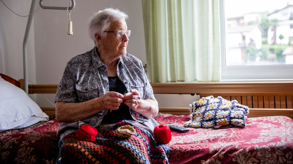 Nursing home resident sitting on the side of her bed
