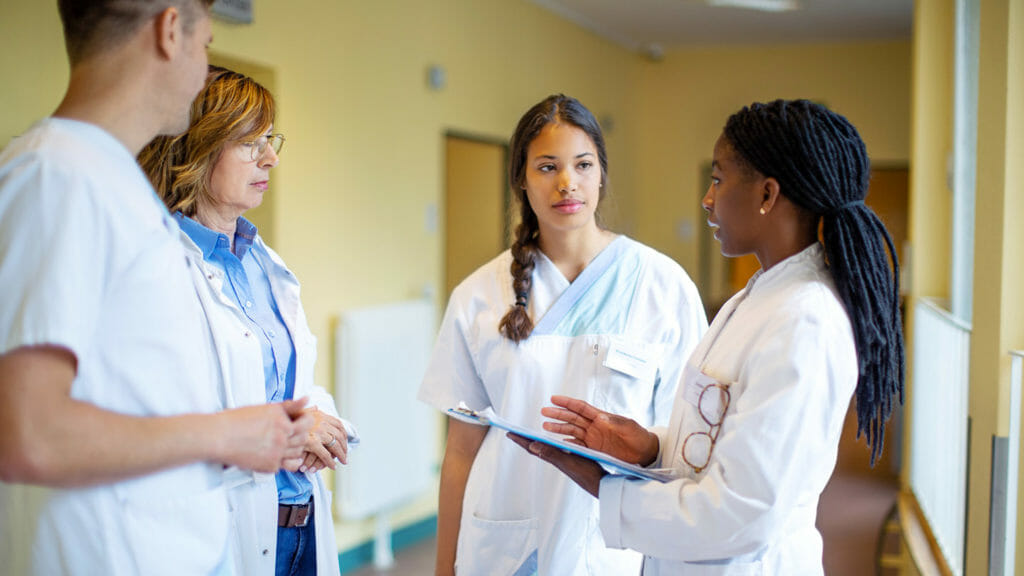 Four healthcare workers having a discussion in a hallway