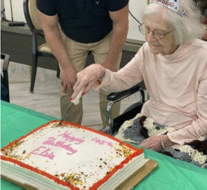 Elsie Cassidy (center, in wheelchair) cuts the cake during a celebration for her 105 birthday.