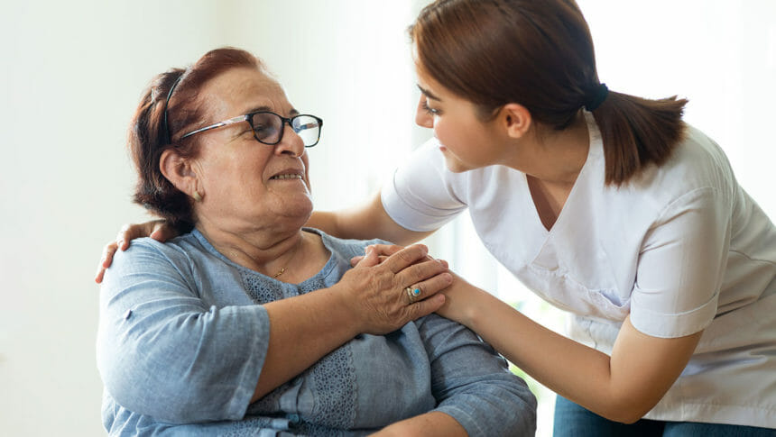 Nurse, CNA cares for nursing home resident, woman