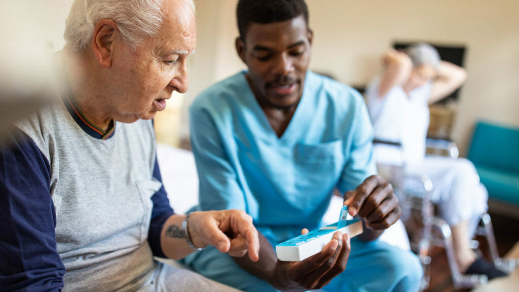 A registered nurse helps a nursing home resident with his medications