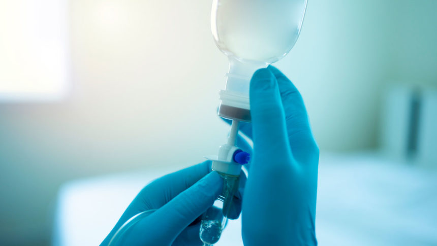Image of gloved hands readying IV bottle; Credit: Getty Images