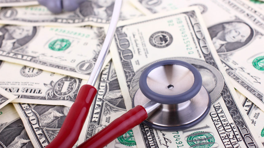 A stethoscope on top of a pile of money