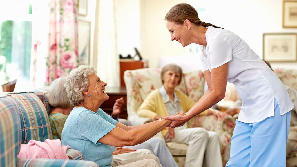 A nursing home worker smiling and helping residents