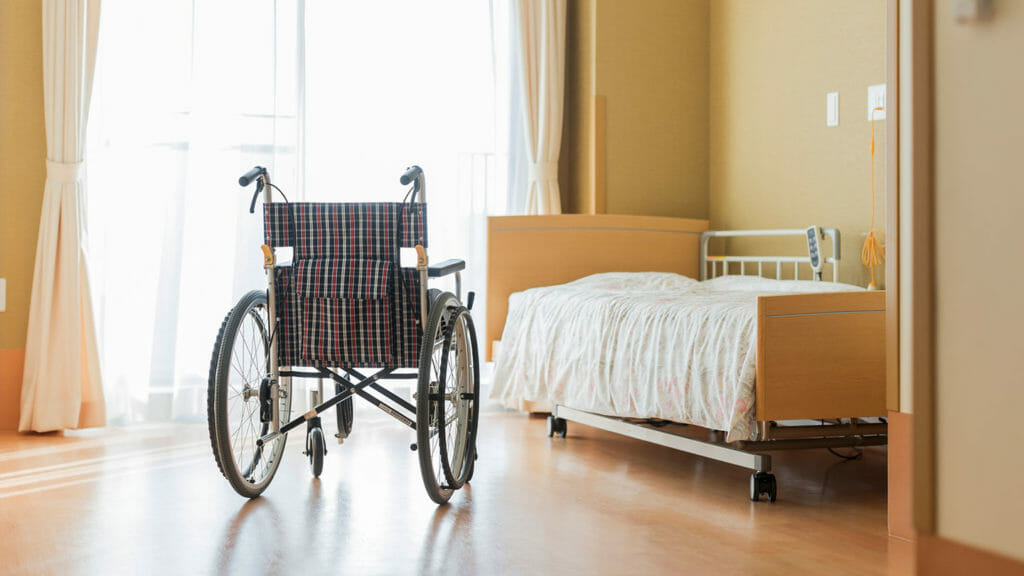 Empty nursing home bed and wheelchair