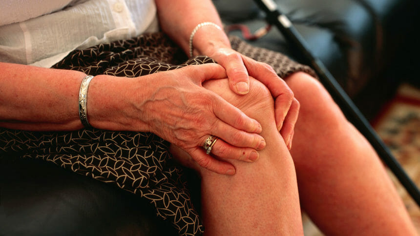 Close up of seniors' hands holding painful knee