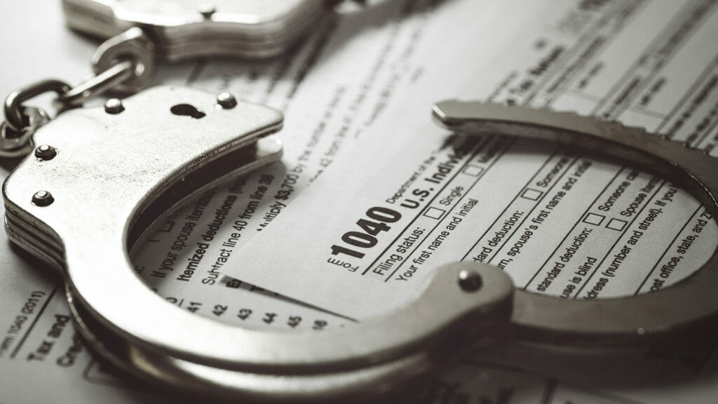 Handcuffs sit on top of tax documents