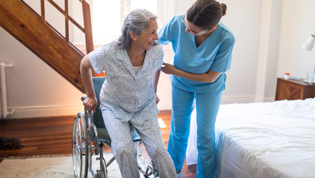 A nurse helps a resident stand up