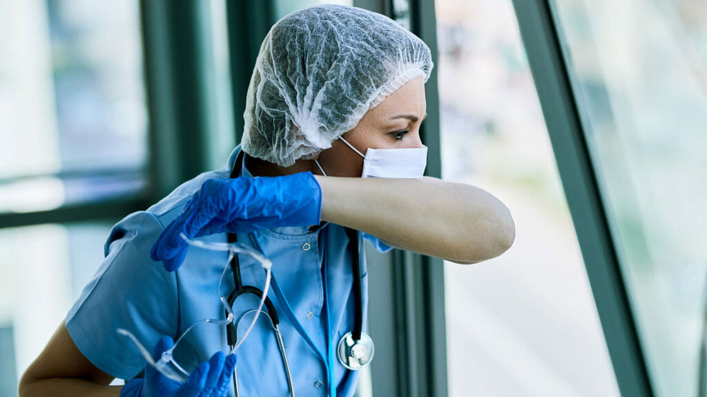 A sick nurse sneezes into her arm