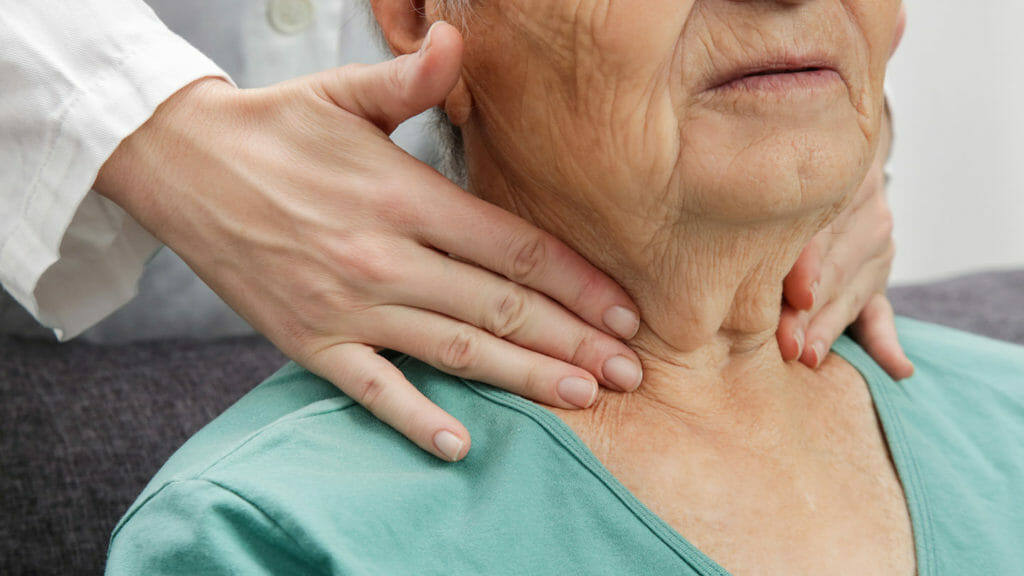 Doctor examining senior woman's thyroid glands or tonsils