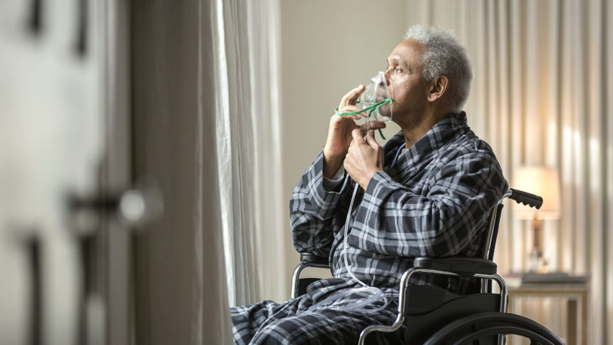 Image of senior African American man in wheelchair breathing with mask