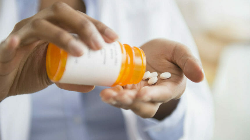 Doctor with pill bottle, spilling medication into hand