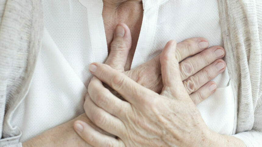 Close-up image of senior woman holding her chest.