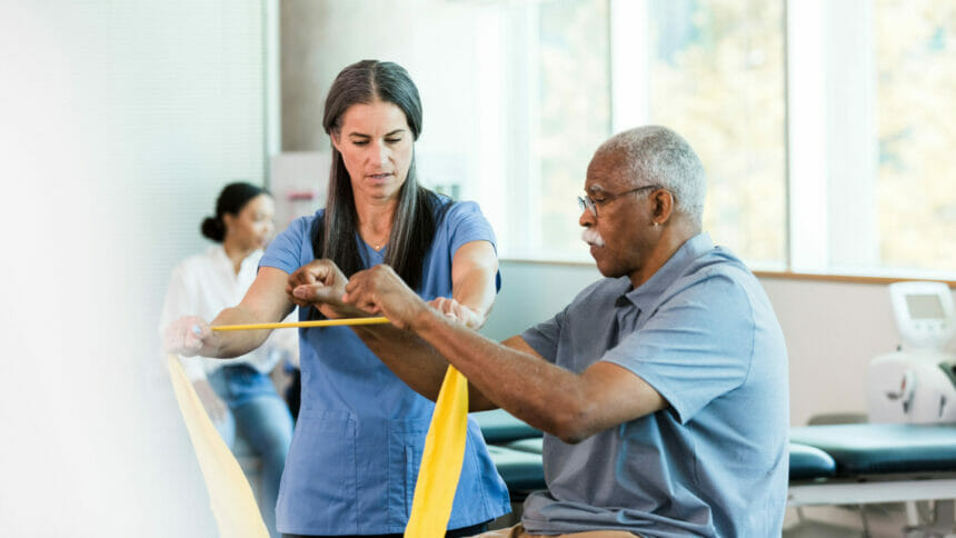 therapist and patient in a therapy session using a yellow exercise band